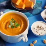 Orange pumpkin soup served in a bowl with a seed garnish