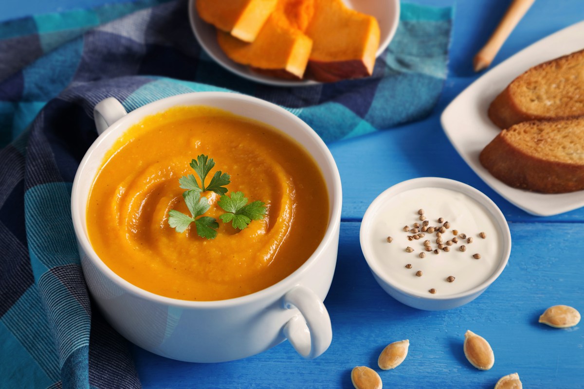 Orange pumpkin soup served in a bowl with a seed garnish