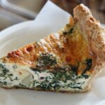 A slice of spinach and cheese quiche on a plate