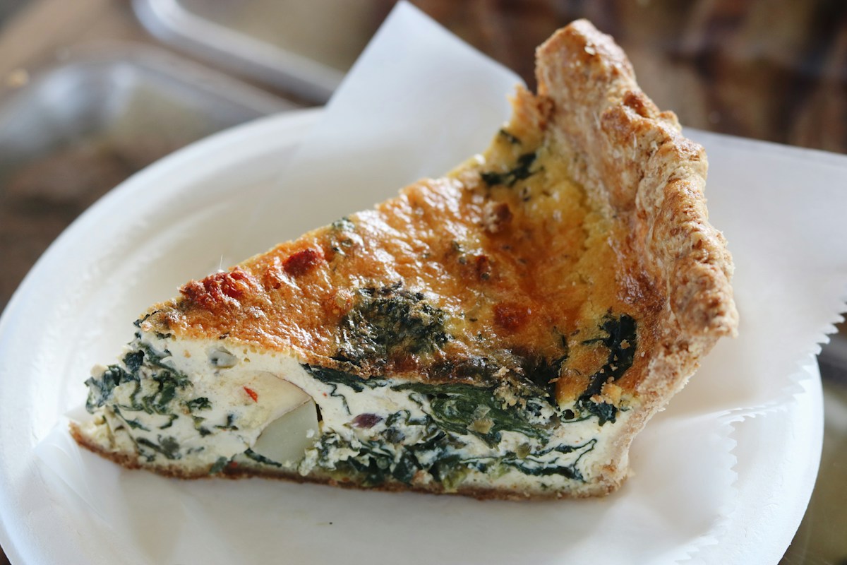 A slice of spinach and cheese quiche on a plate